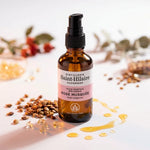 Huile de Rose musquée Bio Saint-Hilaire 50 ml avec graines et gouttes dorées sur fond blanc