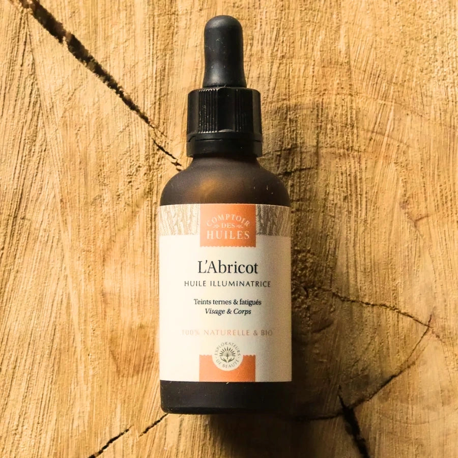 Un flacon de 30 ml d'Huile d'Abricot Bio 30ml Visage & Corps - Comptoir des Huiles, posé sur une planche en bois rustique