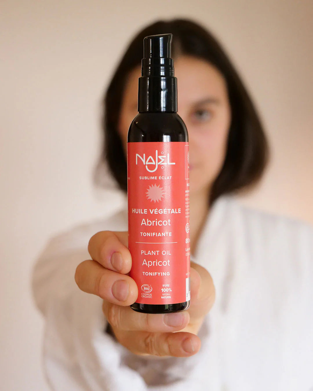 Un flacon d'Huile d'abricot de 80 ml Najel tenu en main