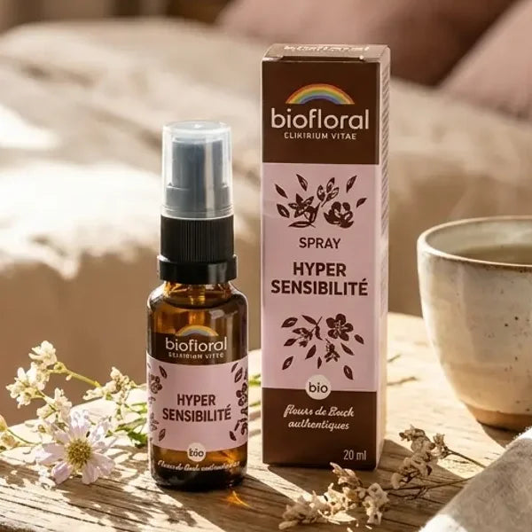 Flacon spray ambré de fleurs de Bach Hypersensibilité bio 20 ml Biofloral, posé sur une table de chevet avec sa boîte et une tisane