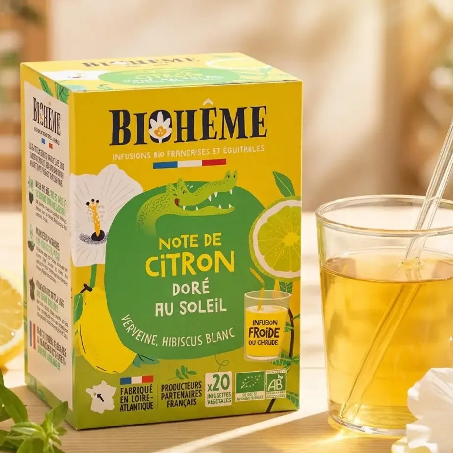 Infusion citron doré Biohême bio en tasse avec citron frais et fleurs d'hibiscus sur table ensoleillée