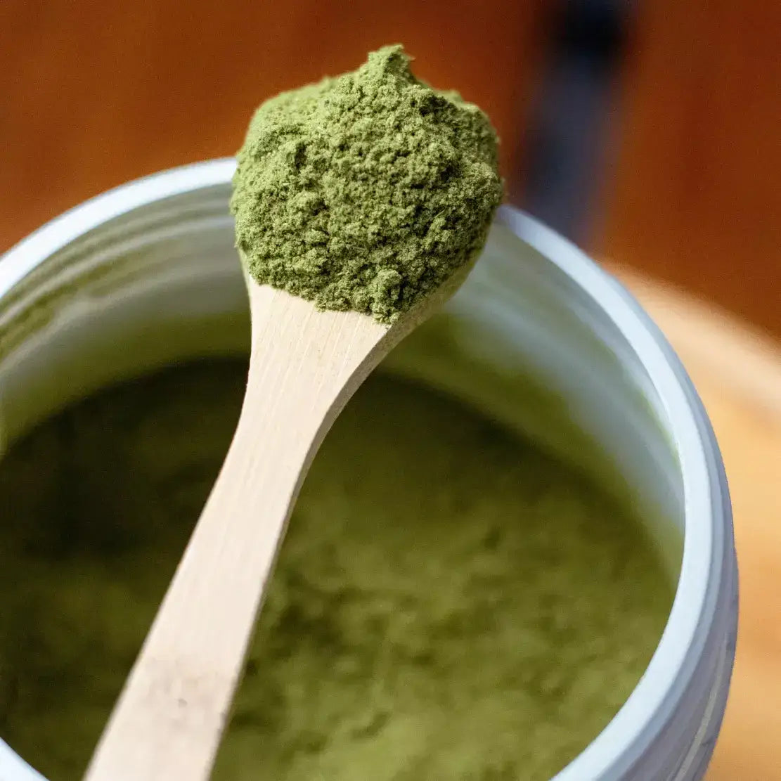 Zoom sur la poudre de Jus d'herbe de blé bio dans une cuillère en bois