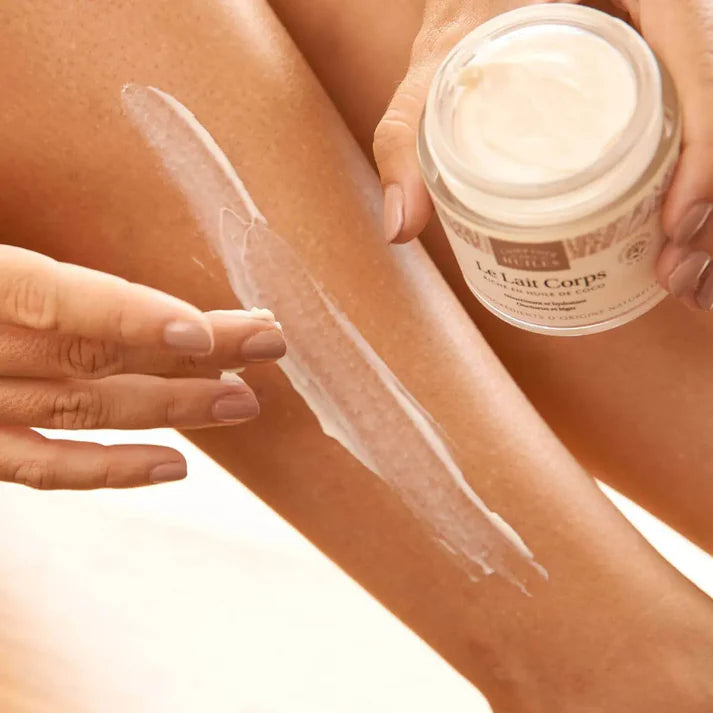 Une femme en train d'appliquer le lait pour le corps comptoir des huiles sur une jambe