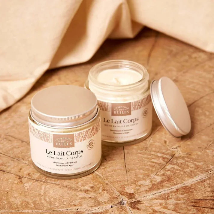 Deux pots de lait pour le corps de la marque comptoir des huiles posé sur un rondin de bois