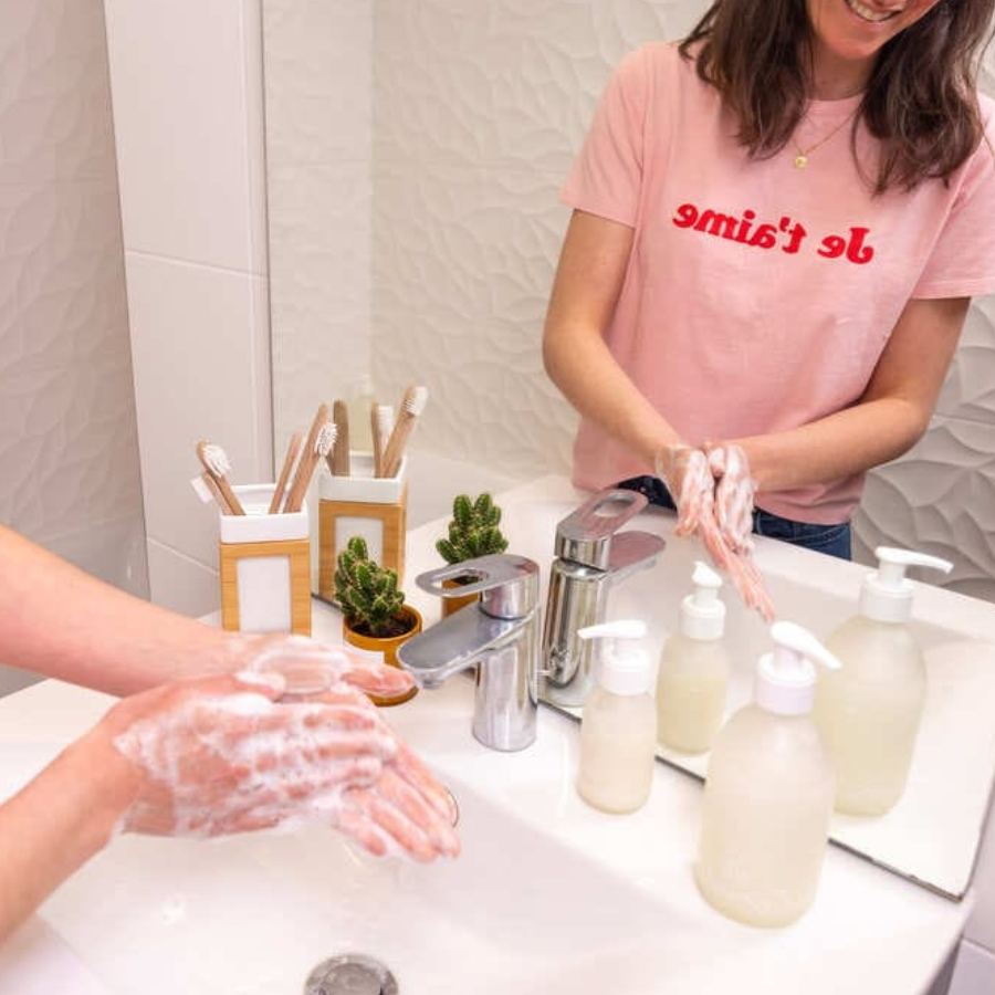 Femme se lavant les mains dans une salle de bain avec le lavant pour les mains à la fleur de coton à diluer, de la marque Pimpant