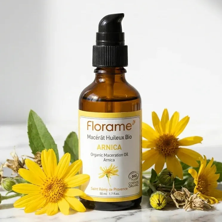Macérât huileux d'Arnica Bio Florame 50ml avec fleurs d'arnica fraîches sur marbre blanc