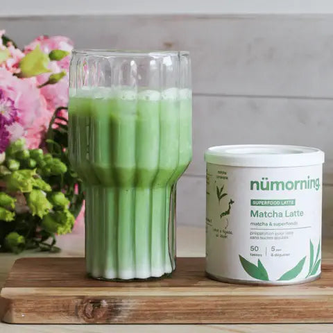 Un pot de Matcha Latte bio nüMorning posé à côté d'un verre de matcha préparé
