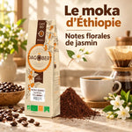 Paquet de café Moka Sidamo Dagobert 500g sur un comptoir de cuisine, tasse de café, grains torréfiés et fleurs de jasmin