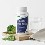 Flacon NAC N-Acetyl Cysteine 600mg SFB entouré de légumes frais et accessoires wellness