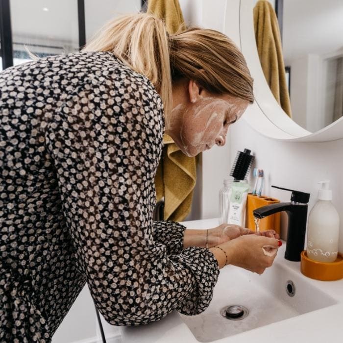 Femme utilisant le nettoyant visage à l'aloé vera à diluer de la marque Pimpant dans sa salle de bain