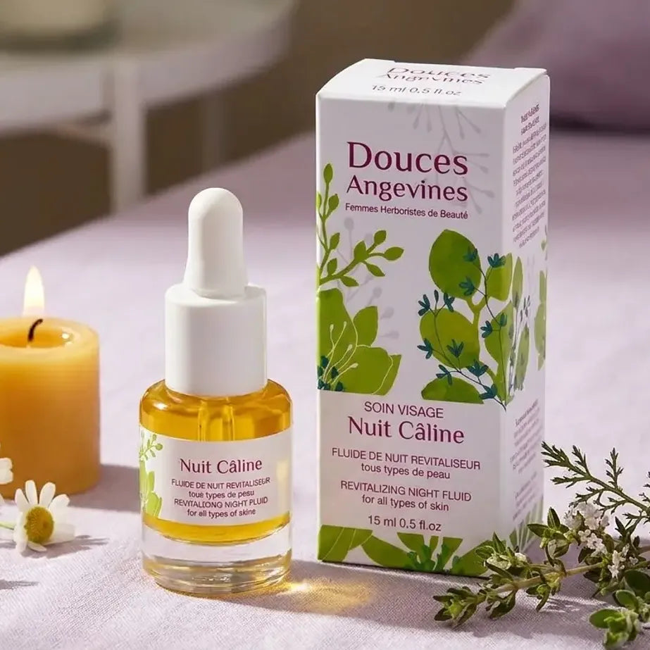 Nuit Câline sérum visage bio Douces Angevines en flacon verre doré sur table de nuit avec fleurs botaniques