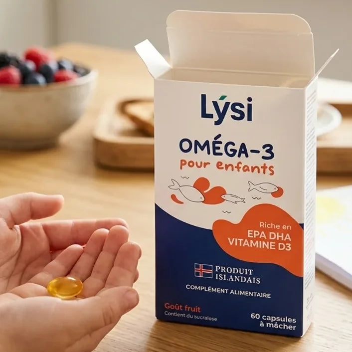 Boîte Oméga-3 Lysi pour enfants avec capsules fruitées à mâcher, posée sur une table de cuisine lumineuse, tenue par de petites mains