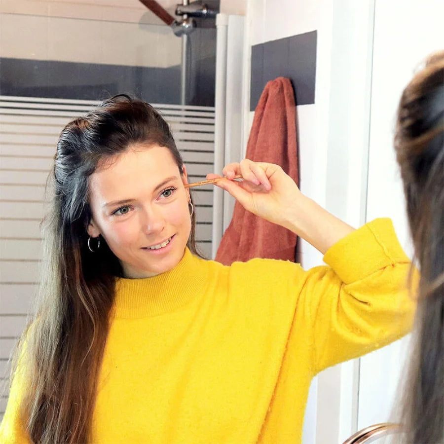 Une fille utilisant un Oriculi en bois de hêtre français de la marque Lamazuna en se regardant dans un miroir