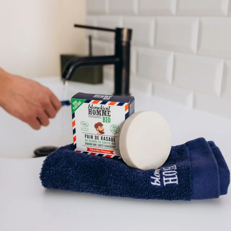 un Pain de rasage bio homme Blondépil Beurre de karité & amande douce posé sur une serviette bleu sur un meuble de salle de bain
