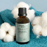 Un flacon de Parfum de lessive Fleur de coton posé sur une serviette bleu, avec du coton à côté