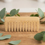 Peigne démêlant Cap Bambou sur surface bois avec feuilles eucalyptus, setting spa naturel