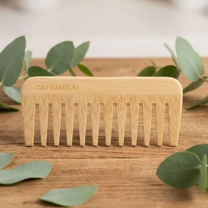 Peigne démêlant Cap Bambou sur surface bois avec feuilles eucalyptus, setting spa naturel