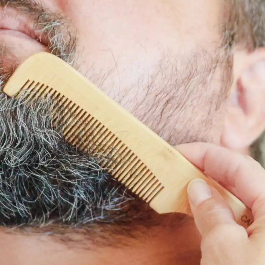 Une femme en train de peigner la barbe d'un homme avec un peigne cap bambou