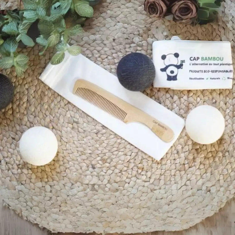 Un peigne cap bambou posé sur un pochon blanc sur un set de table tressé avec des boules noires et blanches