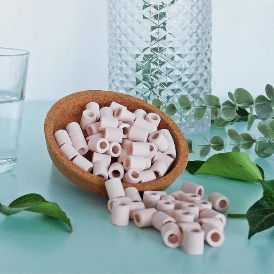 Des Perles de céramique roses Kyuké pour filtrer l’eau du robinet naturellement, dans un bol en bois