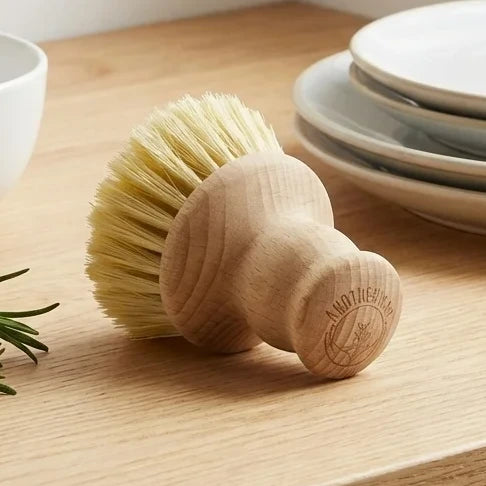 Petite brosse vaisselle Anotherway en bois de hêtre sur surface naturelle avec herbes fraîches