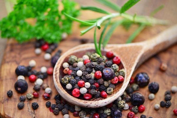 Zoom sur des grains de poivre masala dans une cuillère en bois