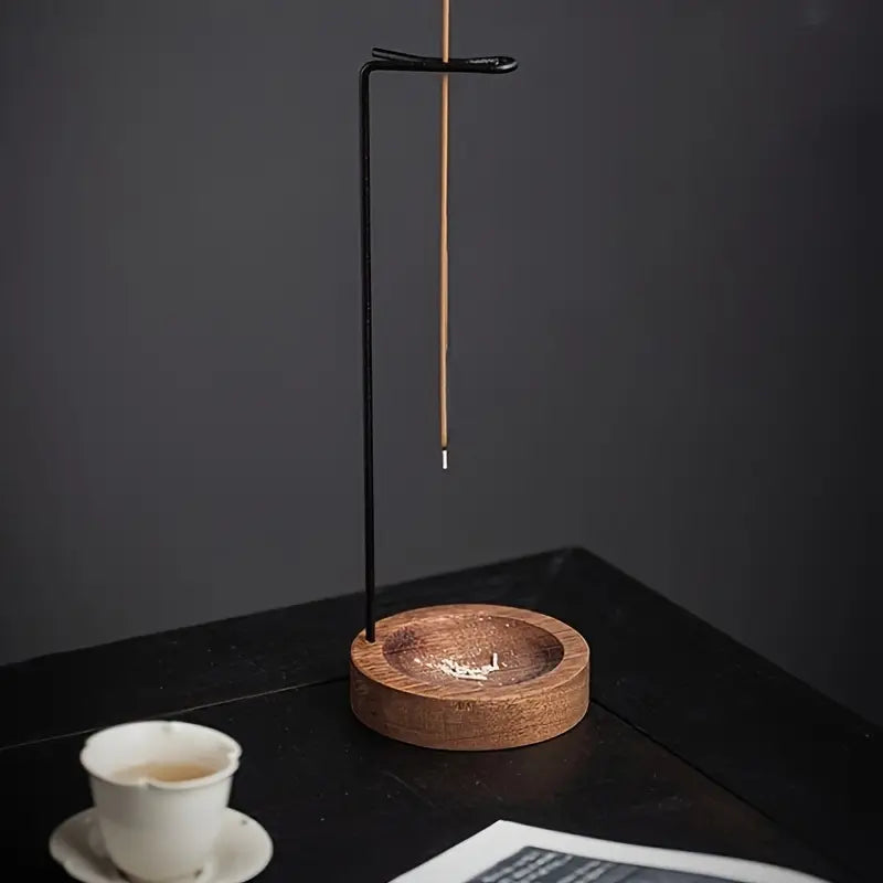 Un Porte-encens suspendu en bois posé sur une table noire