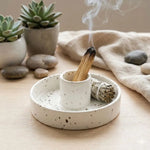 Un porte palo santo moucheté avec un bâton de palo santo fumant et une sague