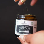 Un pot de 60 grammes de Poudre active de Propolis noire & Argile Verte Ballot-Flurin ouvert et tenu en main