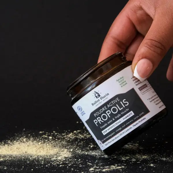 Un pot de 60 grammes de Poudre active de Propolis noire & Argile Verte Ballot-Flurin renversé sur une table noire