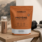 Humble+ Protéine Ressource chocolat sur banc d'entraînement avec haltères et shake protéiné