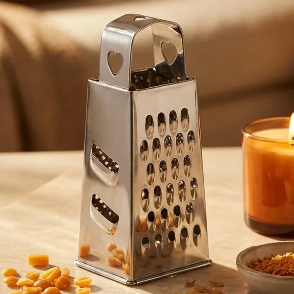 Râpe argentée ByBazz pour carrés d'ambre sur marbre avec copeaux et bougie allumée
