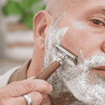Un homme se rasant la barbe avec le rasoir lamazuna