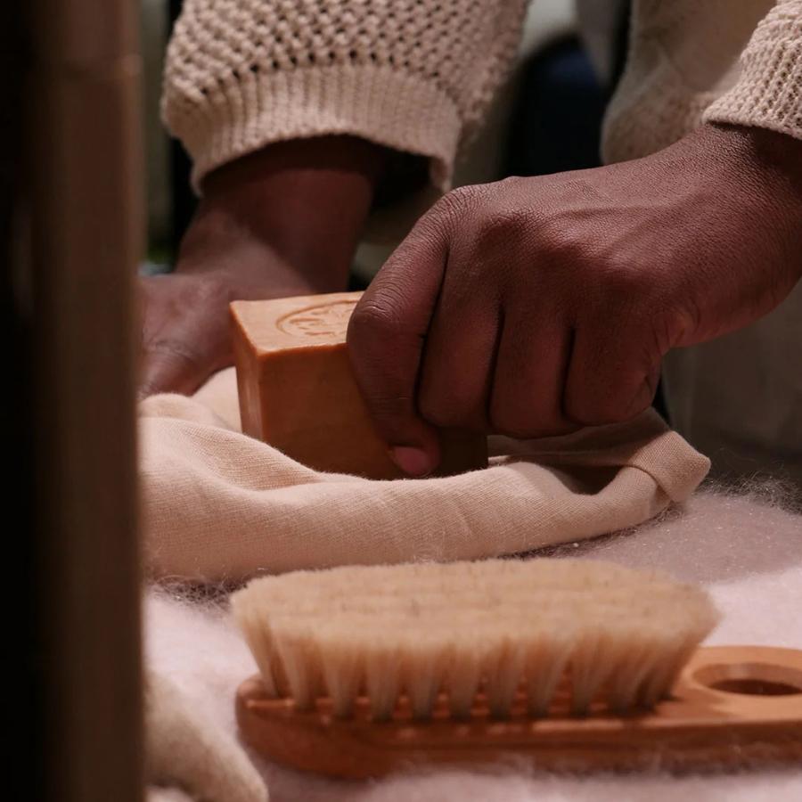 Personne utilisant le Savon d'Alep 200 g de Najel sur un tissu 