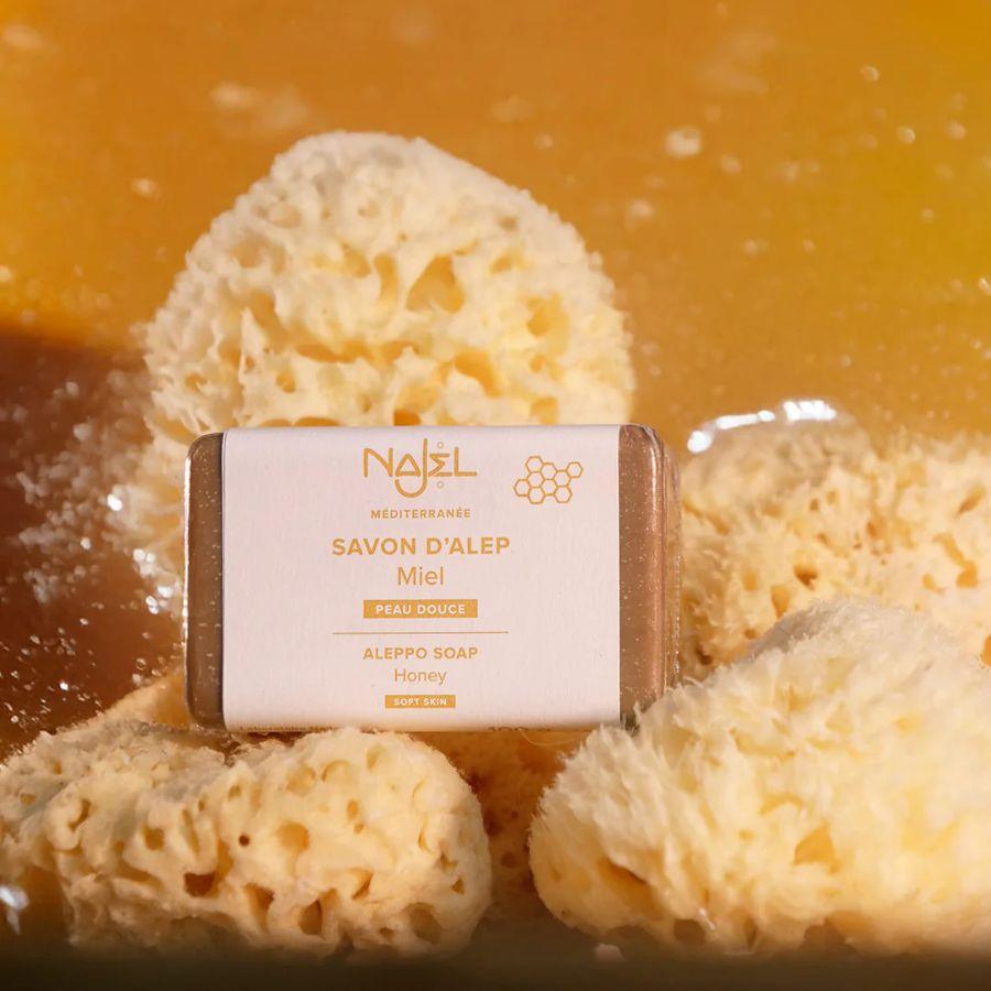 Un savon d'alep au miel de la marque najel posé sur des éponges