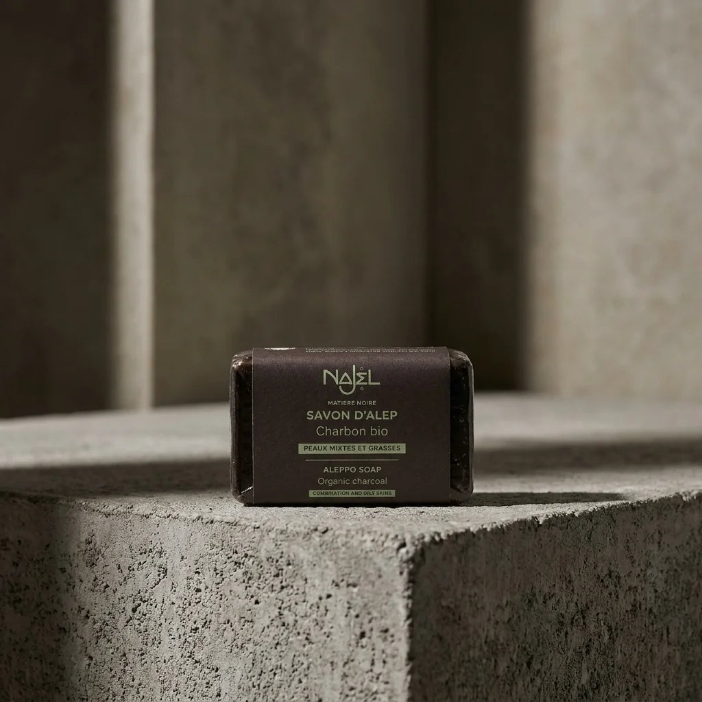 Savon d'Alep au Charbon Bio Najel 100g sur surface texturée, emballage visible