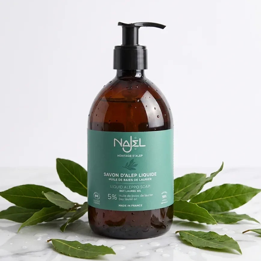 Savon d'Alep liquide Najel 500ml avec feuilles de laurier et gouttes d'eau sur marbre blanc