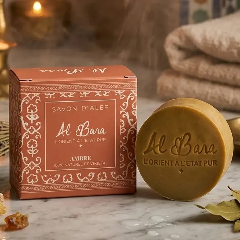 Savon d'Alep parfumé Ambre Al Bara dans son emballage sur marbre avec bougies et ambiance spa