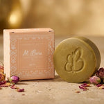 Savon d'Alep Al Bara Musc avec son emballage pêche, pétales de roses séchées sur surface neutre