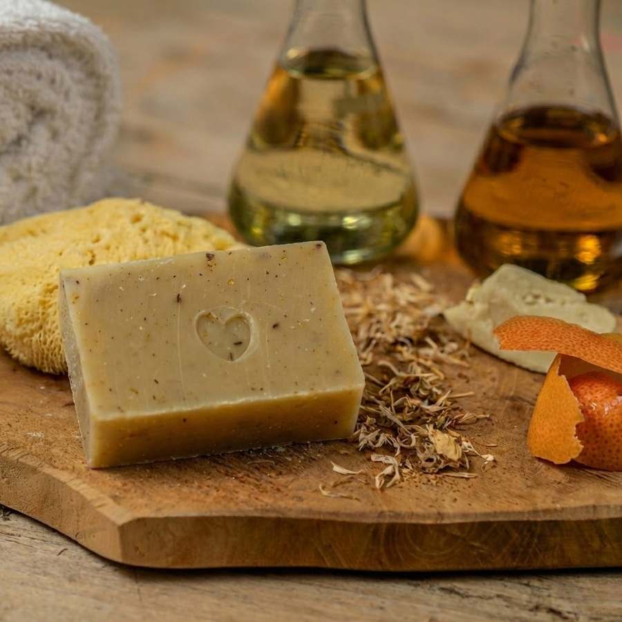 Savon bonne humeur, shampoing brillance, calendula & petit grain bigarade de la marque Jolis Baumes posé une surface en  bois 
