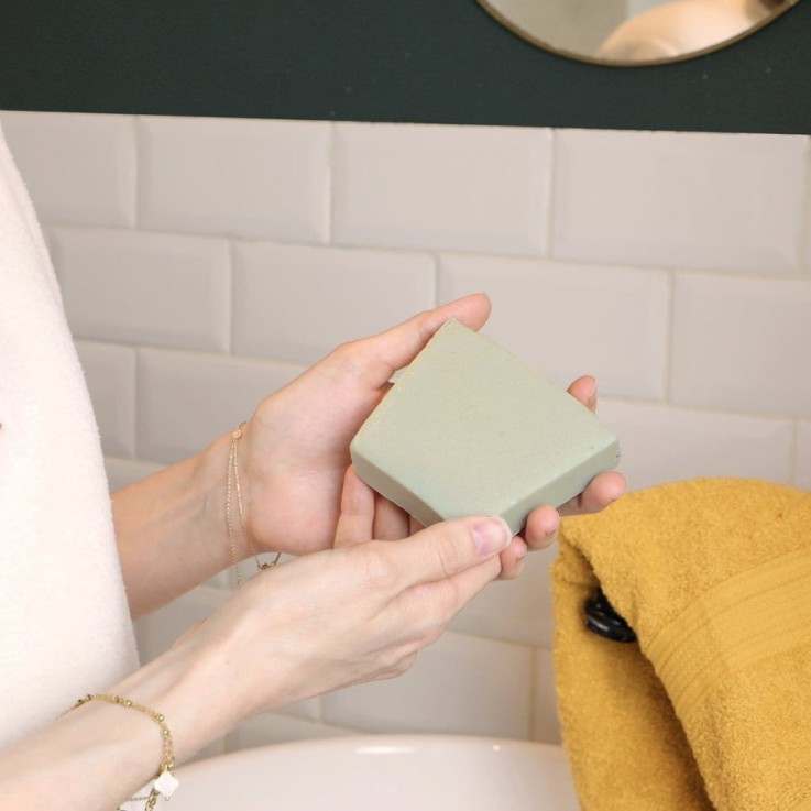 Un savon pour peaux à imperfections de 100 g de la marque Comme Avant tenu en main
