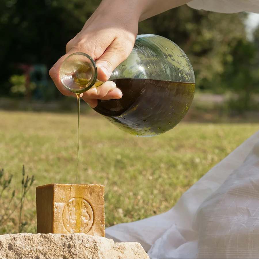 Huile d'olive versée sur le savon d'alep pur olive, en extérieur