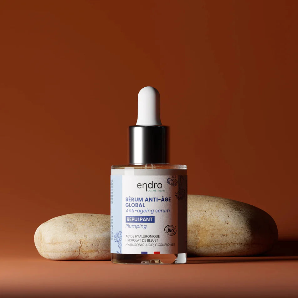 Un sérum anti-âge global repulpant de la marque Endro posé devant deux galets