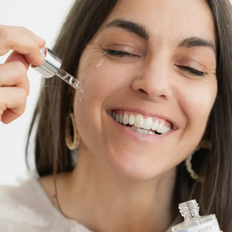 Photo d'une femme en train d'appliquer sur son visage Un sérum anti-âge repulpant à l'acide hyaluronique Endro