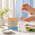 Mains de femme appliquant une goutte de sérum hydratant sur les doigts, à côté d'une recharge écologique 30 ml en sachet kraft et d'aloe vera

Hmm, let me check length: roughly 135 characters, too long. Shorter version:

Mains appliquant une goutte de sérum hydratant, à côté d'une recharge écologique 30 ml en sachet kraft