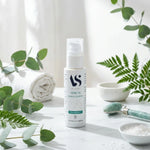 Sérum Jambes Légères Bio Arc en Sels flacon blanc avec étiquette teal, entouré d'éléments botaniques