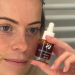Femme tenant le sérum luminescence Arcs en Sels à côté de son visage