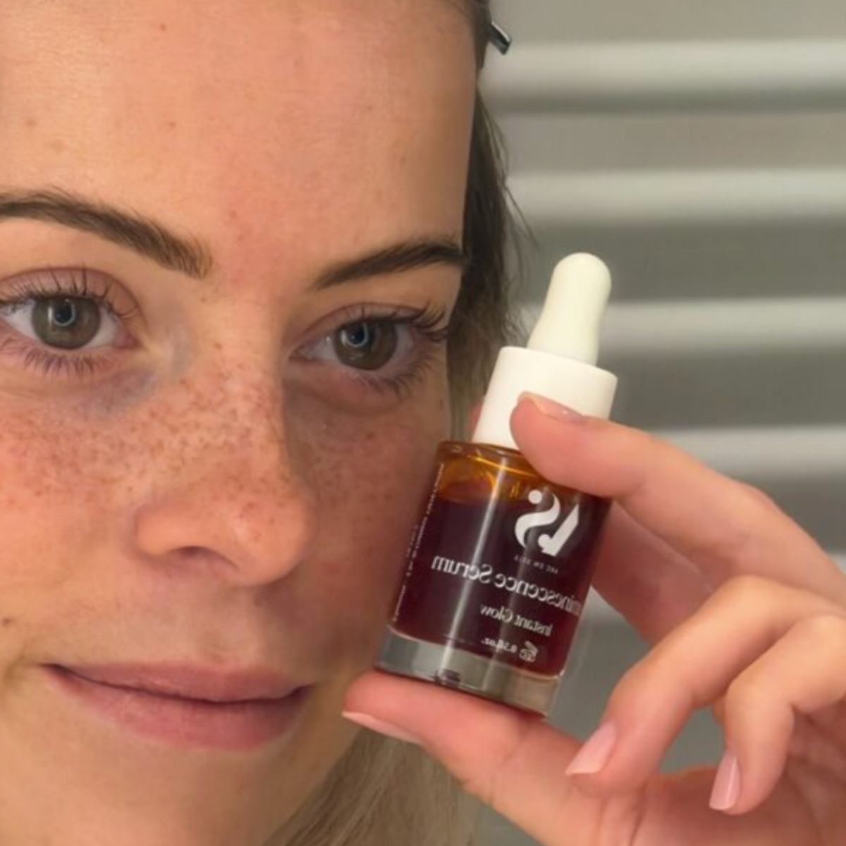 Femme tenant le sérum luminescence Arcs en Sels à côté de son visage