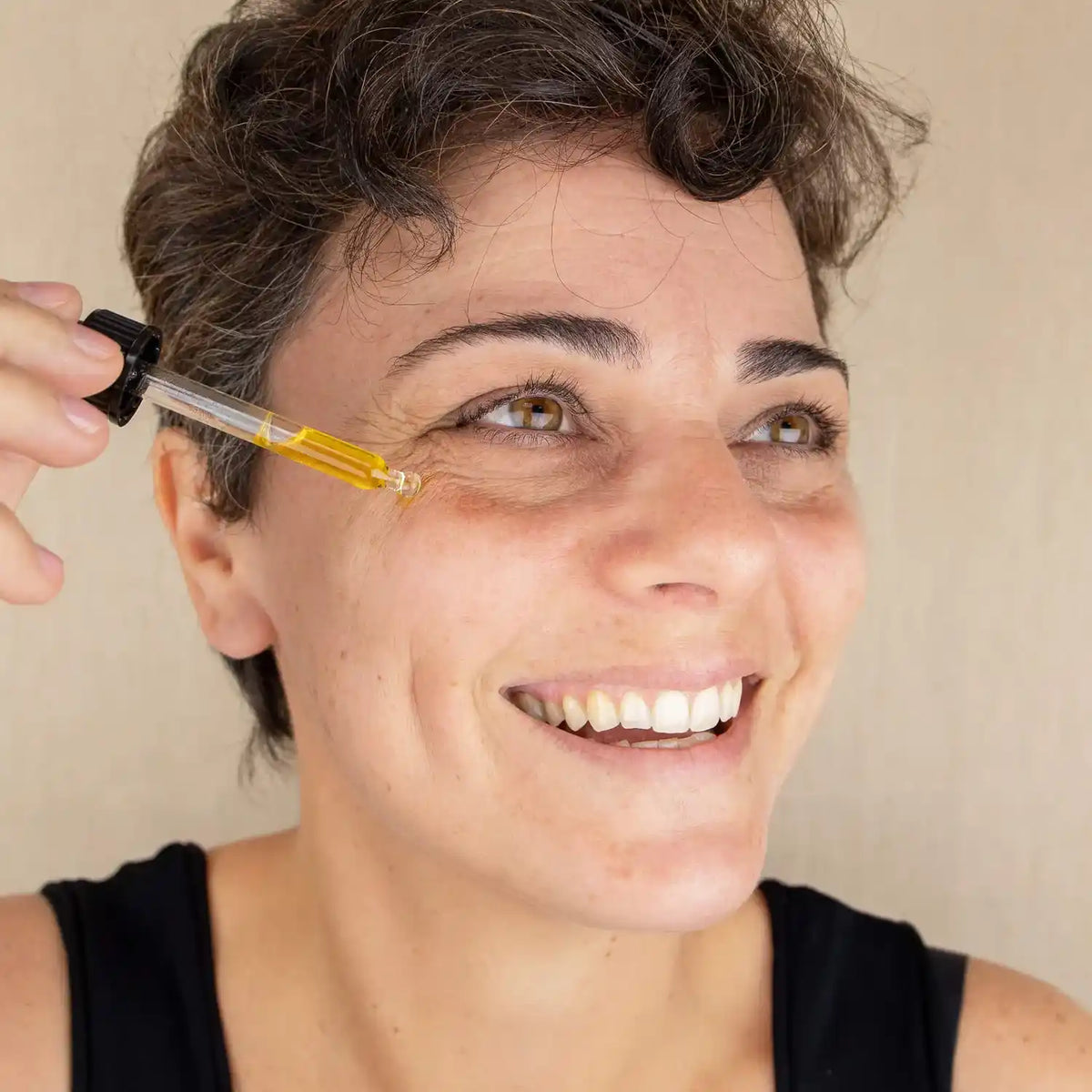 Une femme en train d'appliquer du sérum visage anti-âge de 30 ml de la marque Comme Avant sur son visage