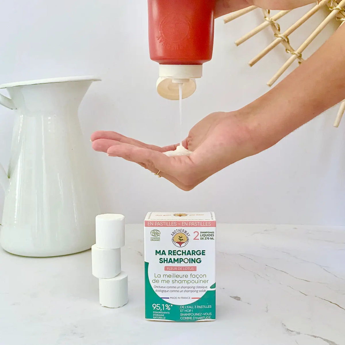 Pack de shampoing fleur de lotus bio de 6 pastilles de la marque Anotherway à côté d'un flacon rechargeable